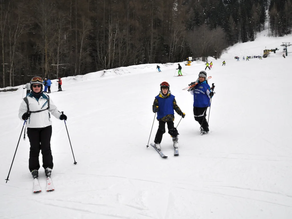 Drei Skifahrende kommen nebeneinander den Hang herunter.